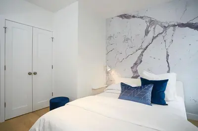 a bedroom with a white bed with blue pillows at Montreal Contemporary Apartment Free Parking in Montréal
