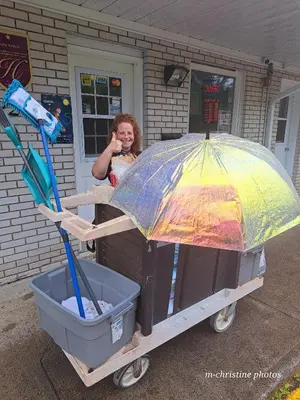 a little girl standing next to a cart with an umbrella at Motel Bonsoir in Joliette