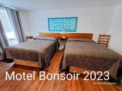 a hotel room with two beds and a desk at Motel Bonsoir in Joliette