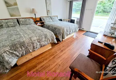 a bedroom with two beds and a desk with a chair at Motel Bonsoir in Joliette