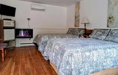 a hotel room with two beds and a tv at Motel Bonsoir in Joliette