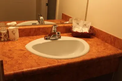 a bathroom counter with a white sink and a mirror at Auberge - Motel Le Pigeonnier in Farnham
