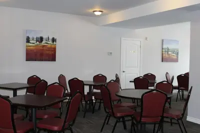 a conference room with tables and chairs and paintings at Auberge - Motel Le Pigeonnier in Farnham