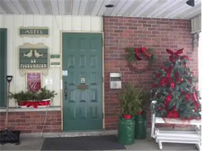 a brick building with a green door and a christmas tree at Auberge - Motel Le Pigeonnier in Farnham