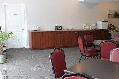 a waiting room with tables and chairs and a kitchen at Auberge - Motel Le Pigeonnier in Farnham