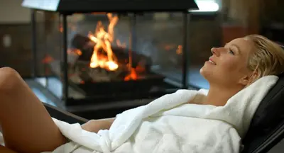a woman laying in a towel in front of a fireplace at Kinipi Spa Nordique & Hebergement in Trois-Rivières