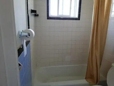 a bathroom with a tub and a toilet and a window at Motel Montreal in Notre-Dame-de-l'Île-Perrot
