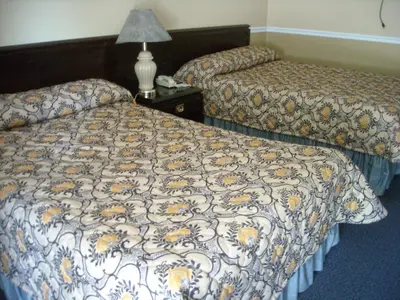 a hotel room with two beds and a table with a lamp at Motel Montreal in Notre-Dame-de-l'Île-Perrot