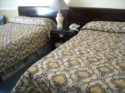 a hotel room with two beds and a table with a lamp at Motel Montreal in Notre-Dame-de-l'Île-Perrot
