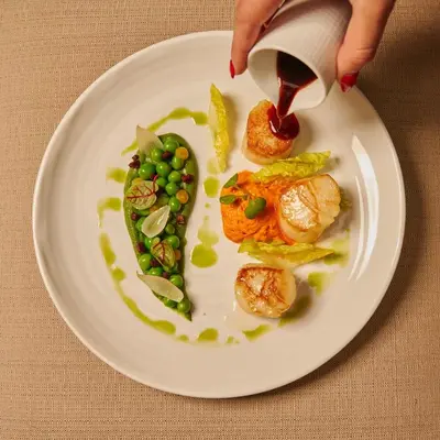 a person pouring sauce on a plate of food at The Ritz-Carlton, Montreal in Montréal