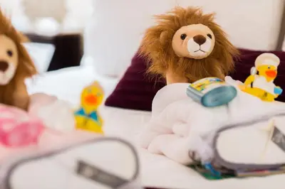 a stuffed monkey sitting on a bed with other toys at The Ritz-Carlton, Montreal in Montréal