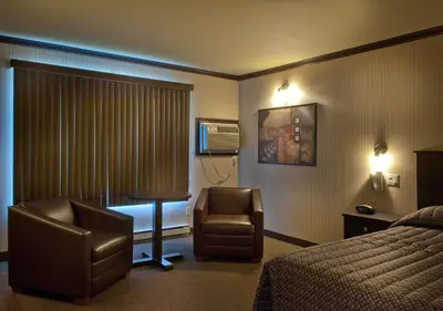 a hotel room with a bed and a chair at Ramada by Wyndham Laval in Laval