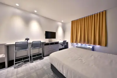 a hotel room with a bed and a desk and a television at Hôtel Ô Laval in Laval