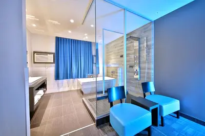 a bathroom with blue chairs and a tub at Hôtel Ô Laval in Laval