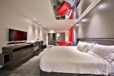 a bedroom with a bed and a desk and a television at Hôtel Ô Laval in Laval