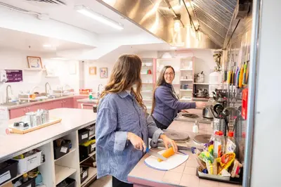 two women standing at a counter in a kitchen at Auberge Saintlo Montréal Hostel in Montréal