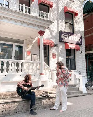 two people playing guitar and a man playing a guitar at Auberge Saintlo Montréal Hostel in Montréal