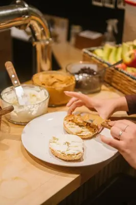 a person is eating food on a plate on a counter at Auberge Saintlo Montréal Hostel in Montréal