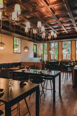 a dining room with tables and chairs and chandeliers at Hotel Montfort in Nicolet