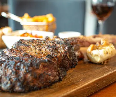 a wooden cutting board with meat and a glass of wine at Hotel Montfort in Nicolet