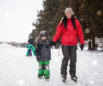 a woman and a child on skis in the snow at Hotel Montfort in Nicolet