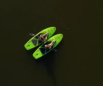 a green kayak in the water with two people in it at Hotel Montfort in Nicolet