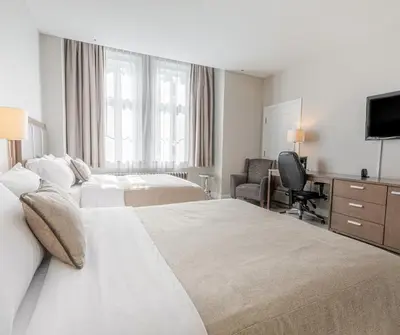 a hotel room with two beds and a television at Hotel Montfort in Nicolet