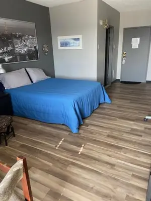 a bedroom with a blue bed and a wooden floor at Motel Populaire in Trois-Rivières