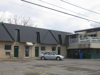 a car parked in a parking lot in front of a motel at Motel Populaire in Trois-Rivières
