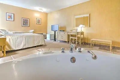 a bathroom with a bath tub and a bedroom at Hotel Motel Penn-Mass in Trois-Rivières