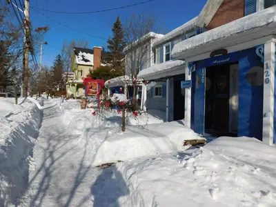 a street covered in snow next to a blue building at Au Coeur De Magog in Magog-Orford