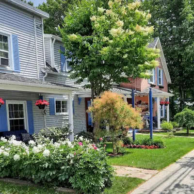 a house with a tree and flowers in the yard at Au Coeur De Magog in Magog-Orford
