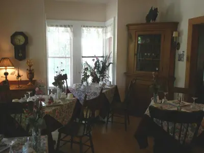 a dining room with tables and chairs and a clock at Ô Bois Dormant B&B in Magog-Orford