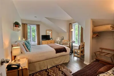 a bedroom with a large bed and a living room at Auberge La Chocolatiere in North Hatley