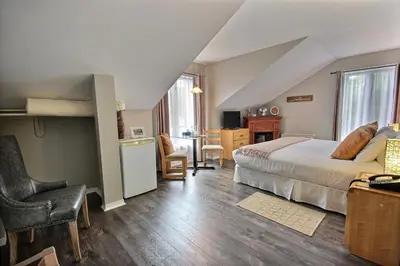a bedroom with a bed and a desk with a chair at Auberge La Chocolatiere in North Hatley