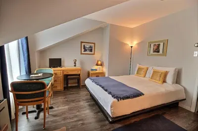 a bedroom with a bed and a desk with a computer at Auberge La Chocolatiere in North Hatley