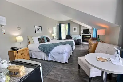 a bedroom with a large bed and a living room at Auberge La Chocolatiere in North Hatley