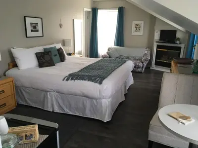 a bedroom with a large bed and a living room at Auberge La Chocolatiere in North Hatley