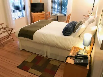 a bedroom with a bed and a desk with a telephone at Auberge La Chocolatiere in North Hatley