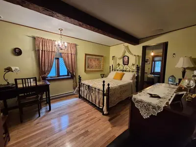 a bedroom with a bed and a desk and a piano at Guesthouse Refuge du Poète Montreal-Longueuil in Longueuil