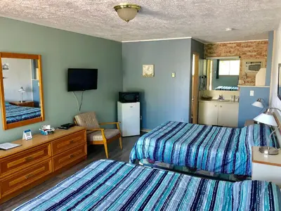 a hotel room with two beds and a television at Motel Belle Riviere in Saint-Jean-sur-Richelieu