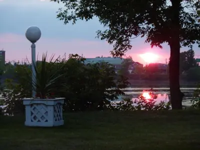 a sunset in a park with a light pole and a lake at Motel Belle Riviere in Saint-Jean-sur-Richelieu