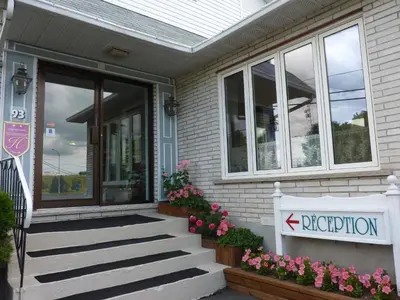 a house with a sign on the front of it at Motel Belle Riviere in Saint-Jean-sur-Richelieu