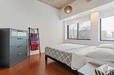 a bedroom with a bed and a dresser and a window at mtlFlats - Condotel Le Luxe in Montréal