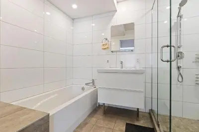 a white bathroom with a tub and a sink at mtlFlats - Condotel Le Luxe in Montréal