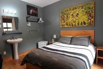 a bedroom with a bed and a sink and a painting at Gite L'Imprévu in Montréal