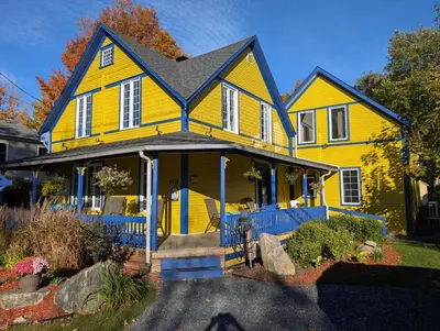 a yellow house with a black roof at Au Saut Du Lit in Magog-Orford