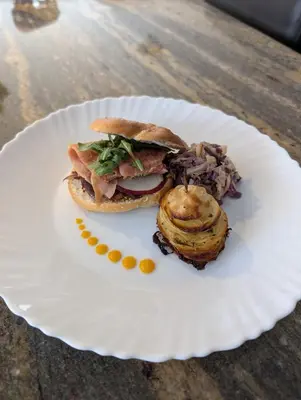 a sandwich on a white plate on a table at Au Saut Du Lit in Magog-Orford