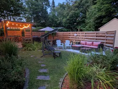 a patio with a pink couch and chairs in a yard at Au Saut Du Lit in Magog-Orford