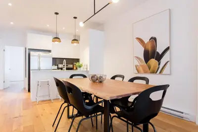 a dining room with a wooden table and black chairs at Hip, Stylish Apartment in Little Italy by Den Stays A in Montréal
